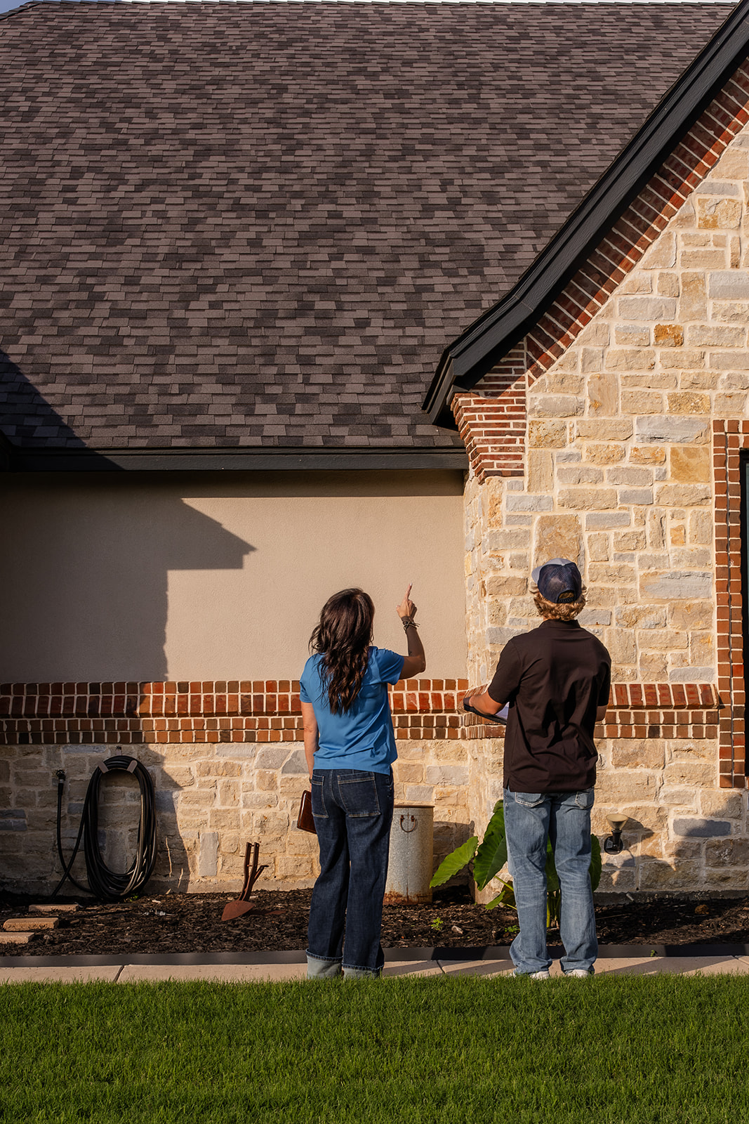 Two people inspecting house exterior