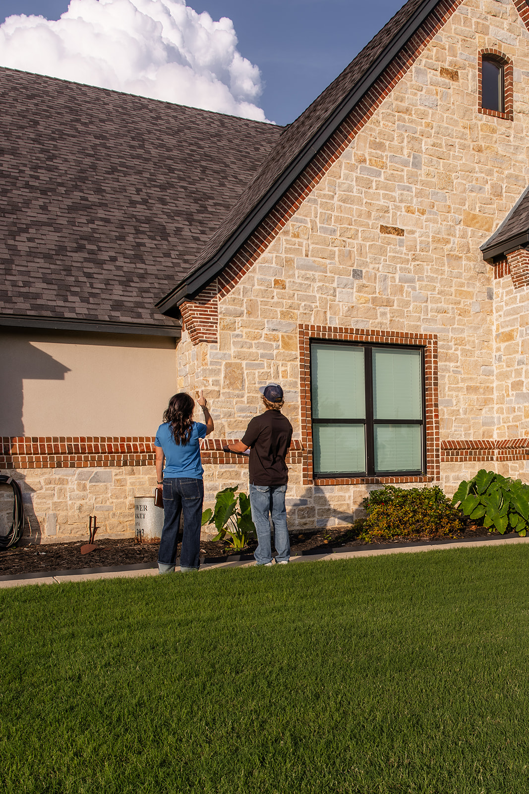 Two people inspecting house exterior